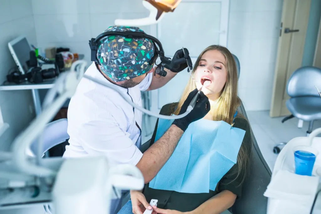 Oral surgeon performing wisdom teeth extraction procedure on female patient at dental office